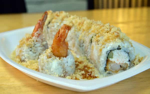 A crispy shrimp tempura sushi roll topped with crunchy flakes and drizzled sauce, delivering a perfect mix of texture and flavor.