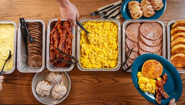 Breakfast catering with pans of bacon, eggs and Canadian bacon