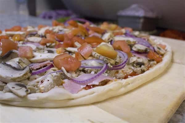 Pizza pie with tomatoes, onions, mushrooms