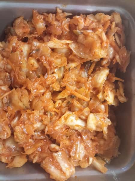 Tray of chopped kimchi with napa cabbage and Korean chili seasoning, a spicy fermented side dish commonly served with Korean cuisine.