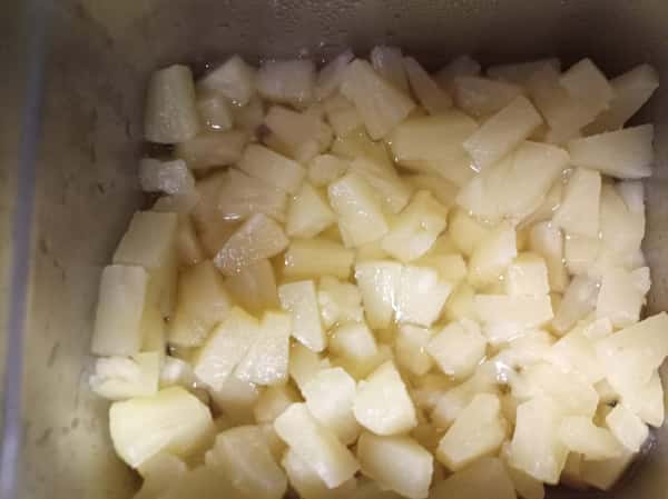 Diced pale yellow fruit pieces in syrup, likely canned pineapple, prepared as a sweet topping or ingredient for desserts and fruit bowls.