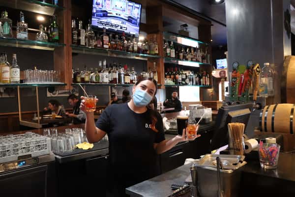 bartender masked with 2 drinks