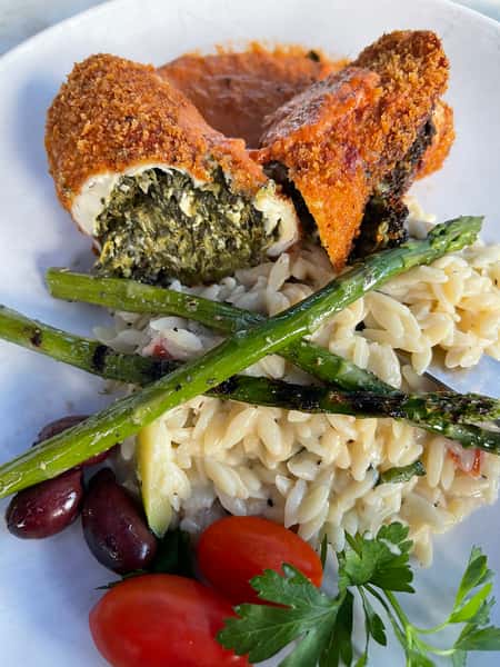 Breaded stuffed chicken filled with spinach and cheese, served over orzo with grilled asparagus, olives, and cherry tomatoes