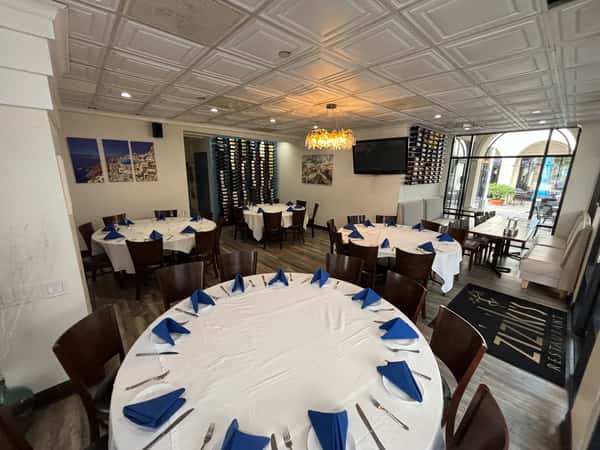 Private dining room with round tables, white linens, blue napkins, wine racks, and chandelier lighting