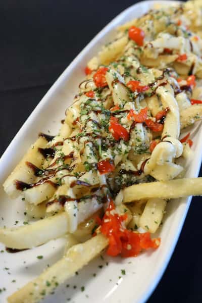 Loaded garlic parmesan fries topped with melted cheese, red peppers, herbs, and balsamic glaze drizzle