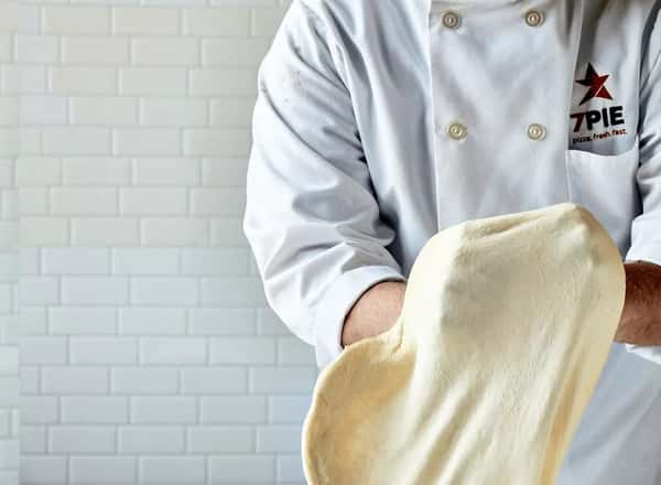 Chef spreading pizza dough