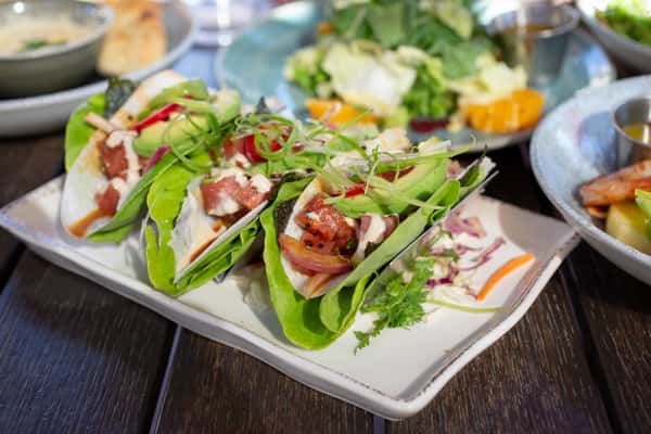 Lettuce wrapped tacos on a white rectangular plate
