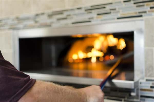 Pizza chef about to take pizza out of wood fired oven