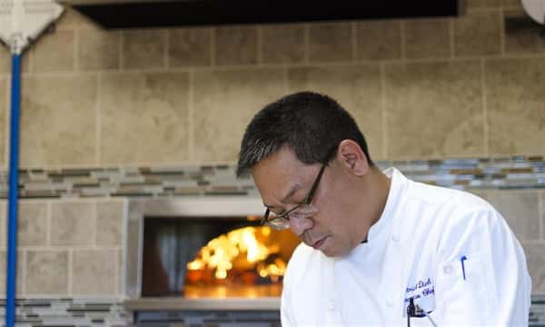 Chef in kitchen in front of pizza oven