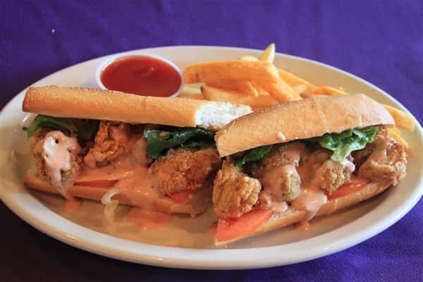 shrimp poboy with lettuce, tomato and sauce, a side of french fries and ketchup
