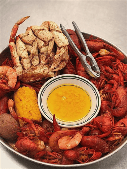 seafood boil with a piece of corn on the cob and a bowl of melted butter