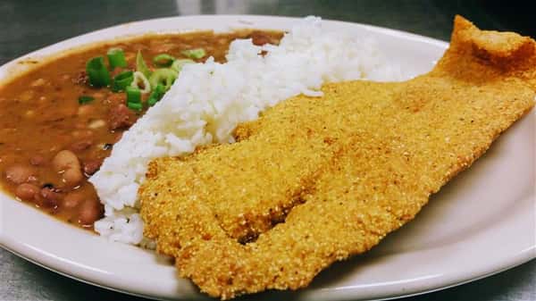 A fried filet of fish with a side of white rice and red beans topped with spring onion