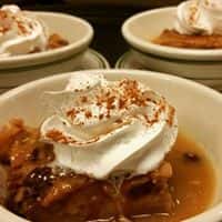 Apple pie in a bowl topped with whip cream and cinnamon
