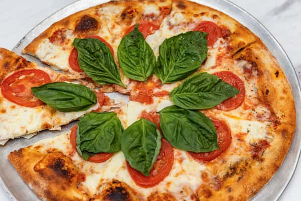 margherita pizza topped with fresh basil, mozzarella, and tomato sauce on a crispy crust
