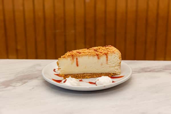 classic cheesecake slice with graham cracker crust and caramel drizzle on plate