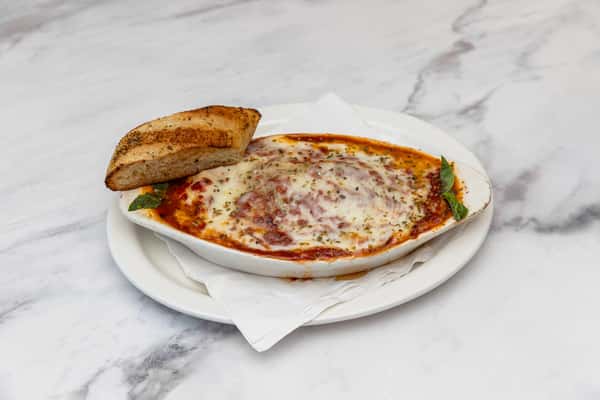 baked lasagna layered with pasta, meat sauce, and melted cheese served with garlic bread