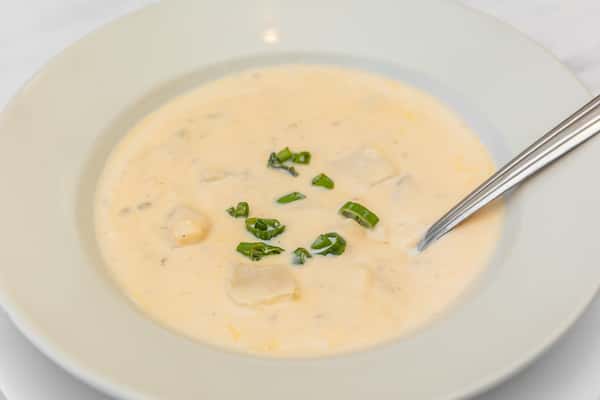 creamy loaded baked potato soup topped with chives in a white bowl