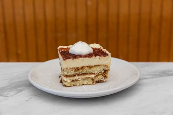classic tiramisu dessert layered with mascarpone cream and cocoa powder on a white plate