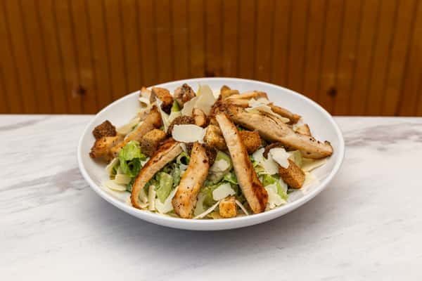 grilled chicken salad with sliced chicken, croutons, and parmesan over fresh greens
