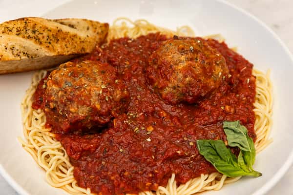 spaghetti and meatballs topped with rich marinara sauce and herbs served with garlic bread
