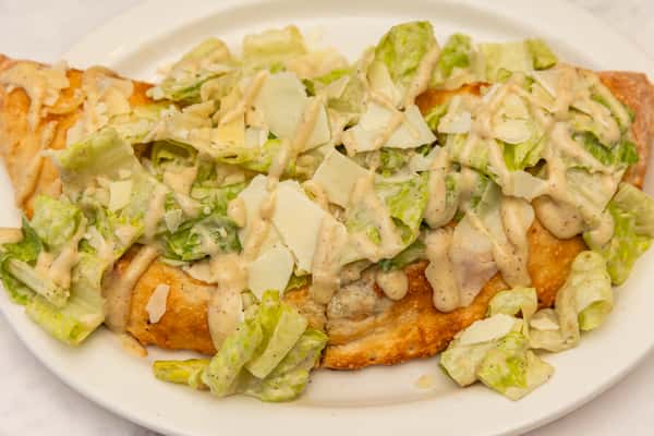 grilled chicken caesar calzone with romaine, parmesan, and creamy dressing on a golden crust