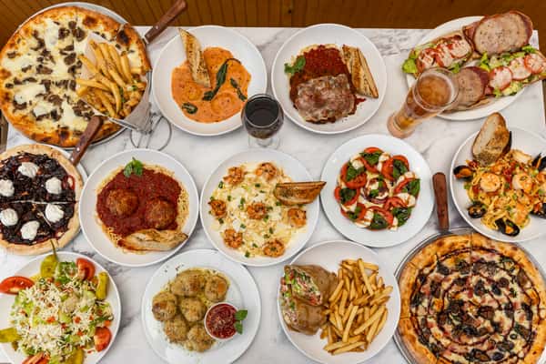 top-down spread of assorted italian dishes including pasta, pizza, salads, and appetizers on a table