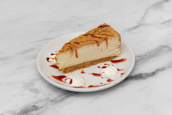 classic cheesecake slice with graham cracker crust and caramel drizzle on plate