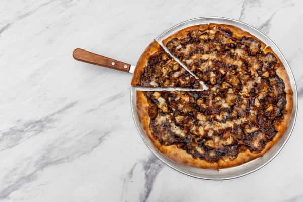 tuscan cowboy pizza loaded with seasoned meat, cheese, and herbs on a golden baked crust
