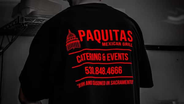 Worker with shirt saying Paquitas Mexican Grill Catering & Events 530-848-4666