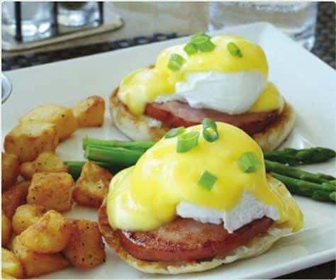 Eggs Benedict with hollandaise sauce, breakfast potatoes, and asparagus