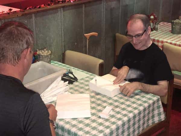 Two men rolling napkins