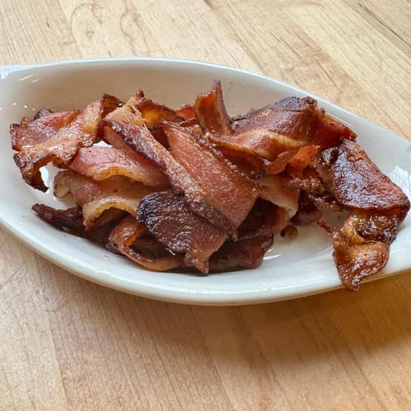 A plate of crispy, golden-brown strips of bacon, arranged neatly on a white dish.