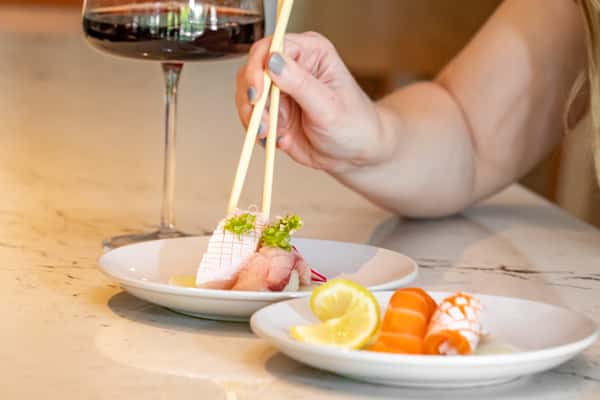 Person using chopsitcks to pick up sushi