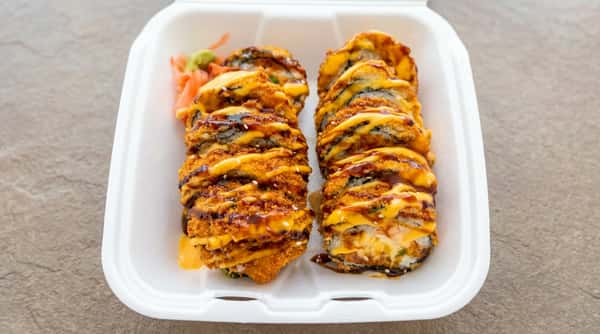 Crispy fried sushi rolls topped with savory sauce and served on a white plate
