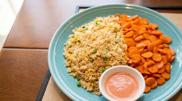 Fried rice served with seasoned carrots and dipping sauce on a white plate