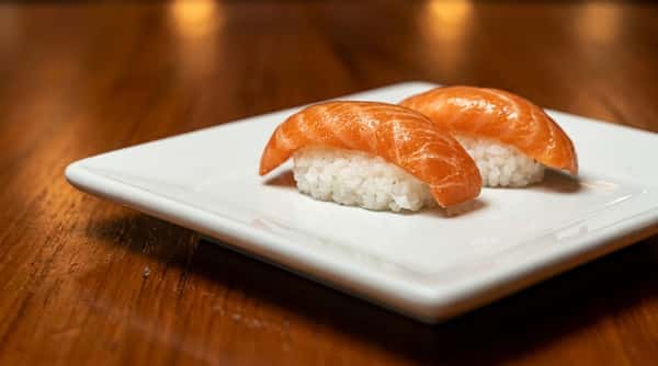 Salmon nigiri sushi featuring fresh salmon over seasoned sushi rice on a white plate