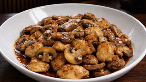 Chicken and mushroom stir-fry sautéed in a savory glaze and served in a white bowl