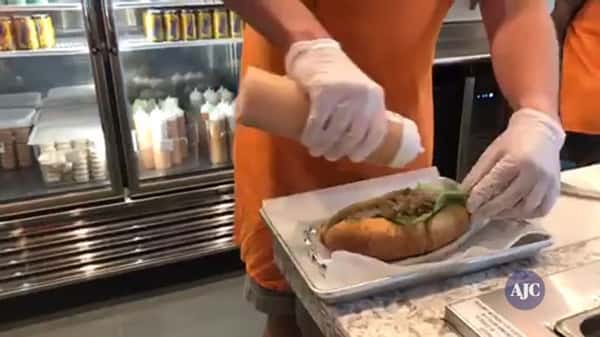 Zunzi's staff adding sauce to a sandwich