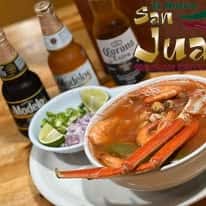 A seafood dish with crab, served with lime, onions, and bottles of beer from brands like Modelo, Corona, and Pacifico.