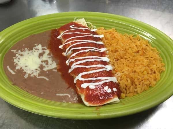 A plate of cheese enchiladas topped with red sauce and sour cream, served with rice and refried beans.