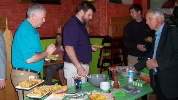 A group of people are serving themselves at a buffet-style table in a vibrant restaurant, with plates of food and drinks.