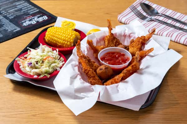 Crispy fried shrimp served with cocktail sauce, coleslaw, corn on the cob, and Southern-style sides.