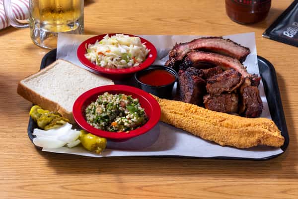 Southern BBQ combo platter with smoked ribs, brisket, fried catfish, cornbread, coleslaw, baked beans, and classic sides.