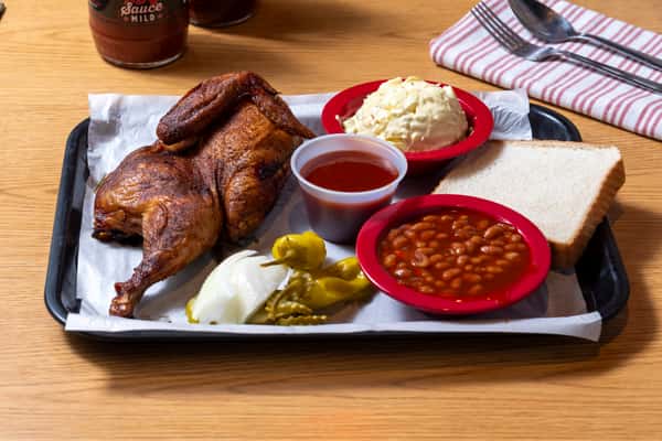 Smoked half chicken served with baked beans, potato salad, white bread, pickles, and BBQ sauce
