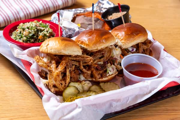 Pulled pork sliders on toasted buns served with pickles, BBQ sauce, and Southern barbecue sides
