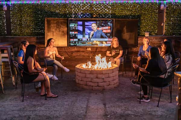 Guests enjoying a private area with a fire pit and flat screen TV for sports fans