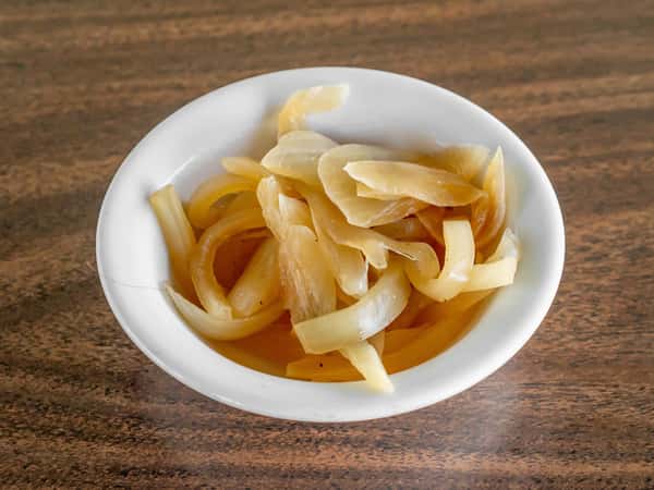 White bowl filled with golden sautéed sweet onions on a dark wood table at Miller's Cafe.