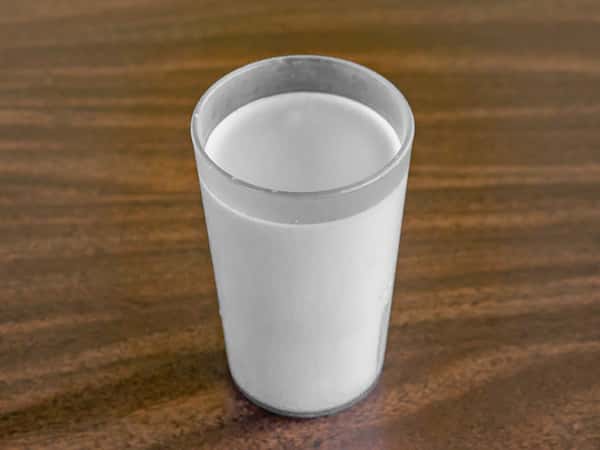 A frosted glass of cold white milk on a dark wood grain table at Miller's Cafe.