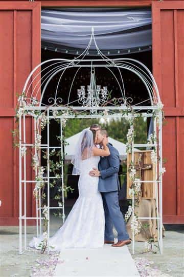 bride and groom kissing in front of a cage