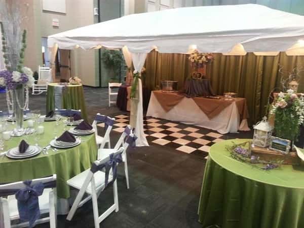 room of tables with tablecloths and napkins with a tent in the background
